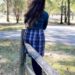 Woman standing in fall leaves wearing plaid wool skirt