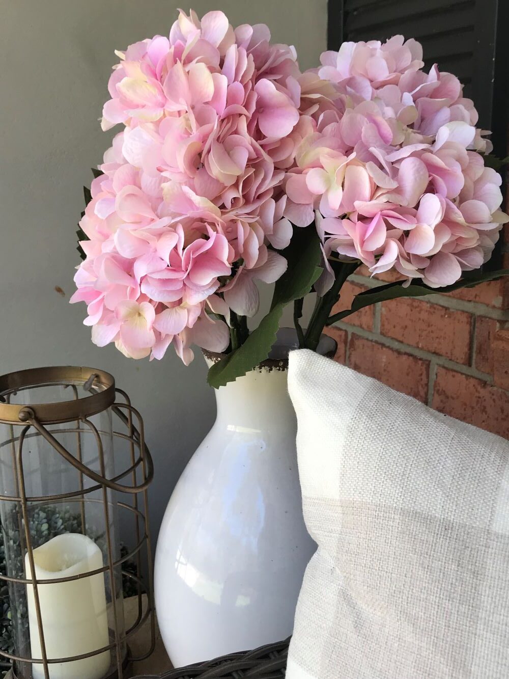 pink faux hydrangeas in white ceramic vase on porch for spring decor from hobby lobby