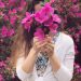 woman holding pink bouquet of flowers in front of face