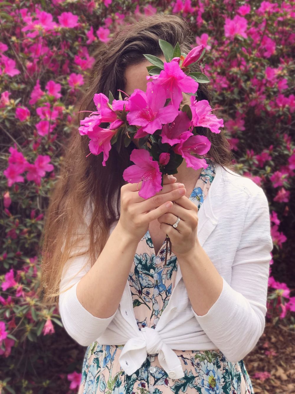 woman holding pink bouquet of flowers in front of face