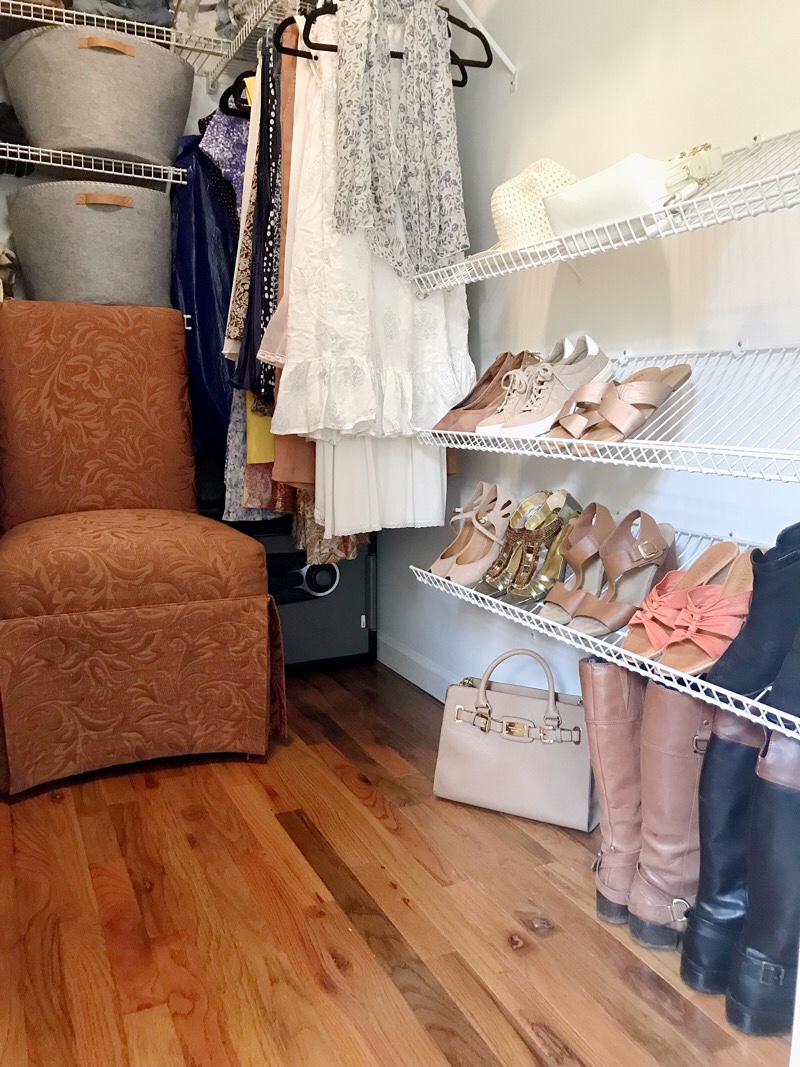 beautiful and organized walk in closet with wood floors, shoe shelves on wall, and a chair to sit